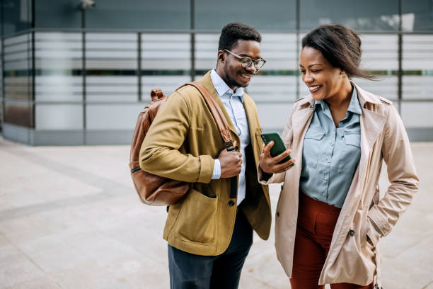 istock Two smiling colleagues using phone in front of their company 1343190401