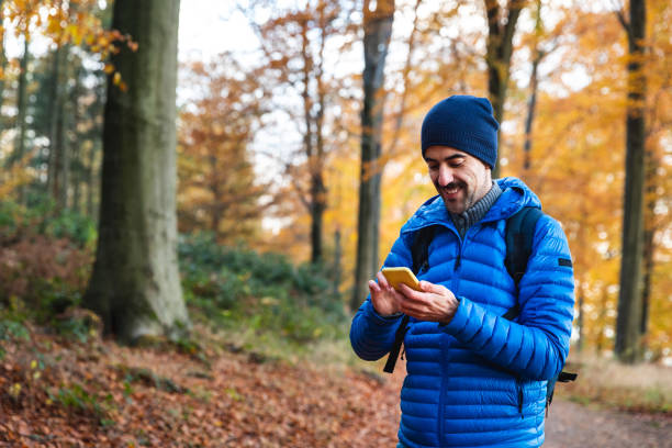 homem caminhando em um caminho na floresta caminhando e verificando seu telefone - staffordshire - fotografias e filmes do acervo