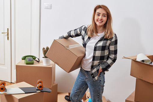 Young woman with cardboard boxes in a new appartment