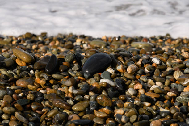 istock Pebbles on the beach close up on the sea surf background, copy space 1343203308