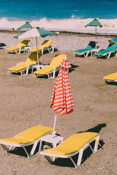 黄色のサンベッドとカラフルな赤と白の傘を持つビーチ。レトロなスタイルのコンセプト - southern usa sand textured photography ストックフォトと画像