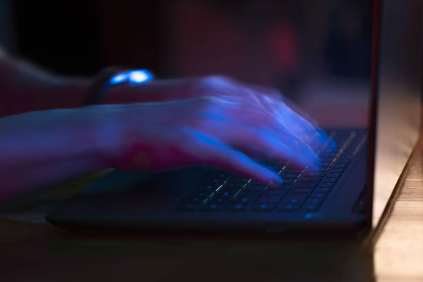 istock Man using laptop in the dark with blue glow of screen 1343213886