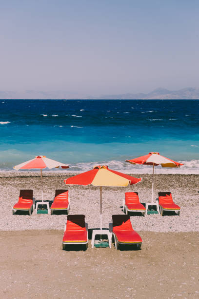 istock Beach with yellow and red sunbeds, sea with waves. Retro styled concept 1343213908