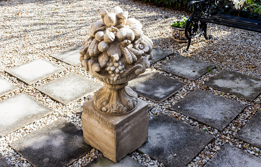 Garden courtyard with elegant cement sculpture, paving and pebbles - seating bench in background