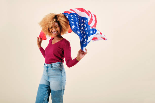istock Smiling young afro woman waving a US flag while standing on an isolated background. 1343225602
