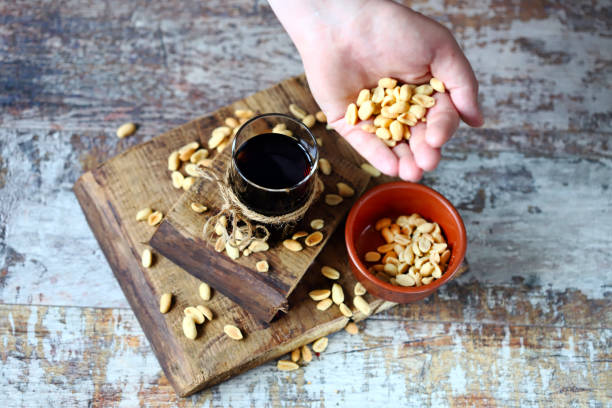 A glass of black soda drink and peanuts. stock photo