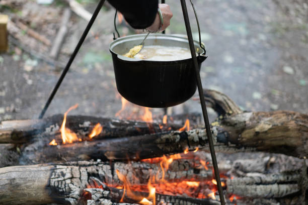 istock Camping outdoors. Cooking bowler hat hung on tripod over bonfire 1343239025