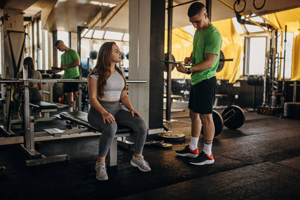 istock Personal trainer and young woman in gym 1343240507