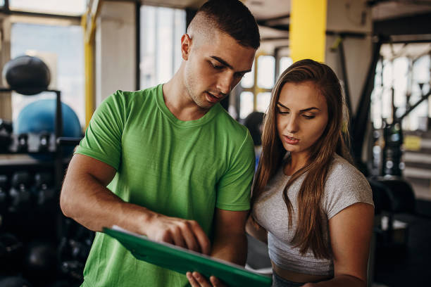 istock Personal trainer and young woman in gym 1343240645