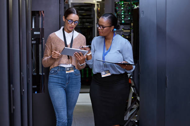 обрезанный снимок двух привлекательных молодых женщин-программистов, работающих вместе в серверной комнате - data center computer programmer women стоковые фото и изображения