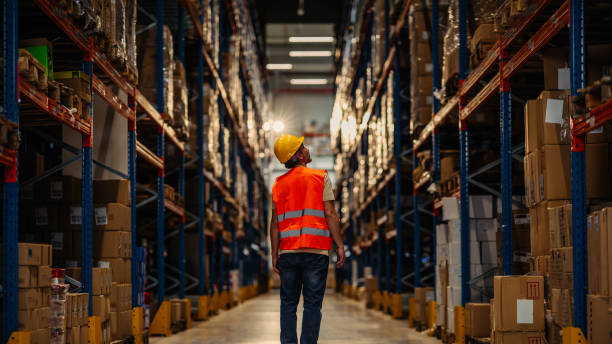 Warehouse worker oversees shelves with boxes stock photo