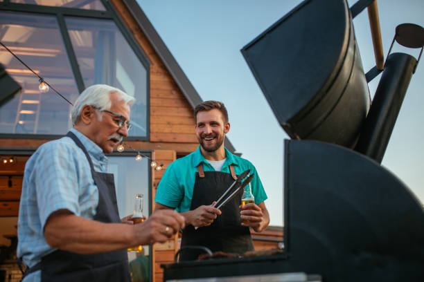 homme heureux et son père faisant un barbecue dans la cour arrière - grilled photos et images de collection