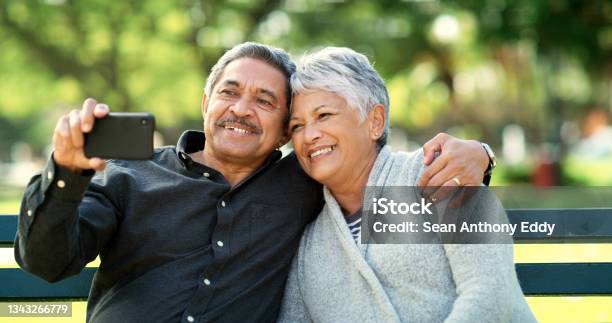 Shot Of An Elderly Couple Taking A Selfie While Sitting On A Bench In A Park - Fotografias de stock e mais imagens de Latino-americano