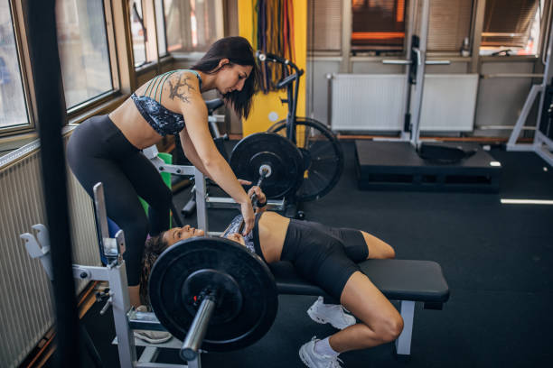 istock Personal trainer assisting a woman in bench press 1343267341
