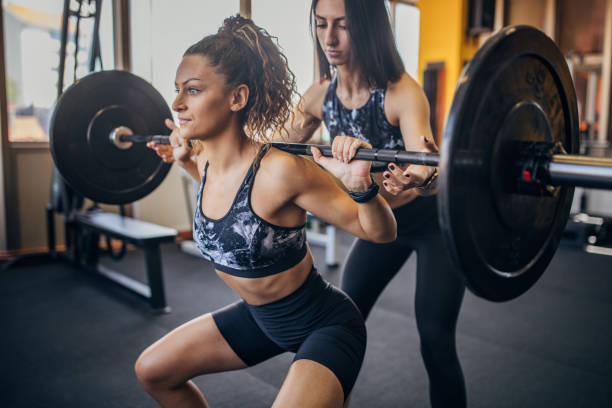 istock Trainer assisting a woman in weightlifting 1343267448