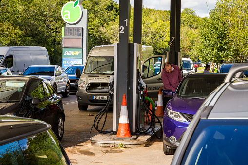 Crawley, UK - 27 September, 2021: cars queue up to fill up with petrol at the gas station during a fuel shortage. Cars are lined up down the road as people rush to panic buy petrol.