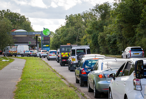 Crawley, UK - 27 September, 2021: cars queue up to fill up with petrol at the gas station during a fuel shortage. Cars are lined up down the road as people rush to panic buy petrol.