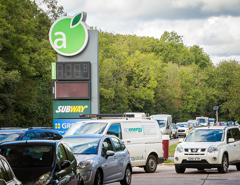 Crawley, UK - 27 September, 2021: cars queue up to fill up with petrol at the gas station during a fuel shortage. Cars are lined up down the road as people rush to panic buy petrol.