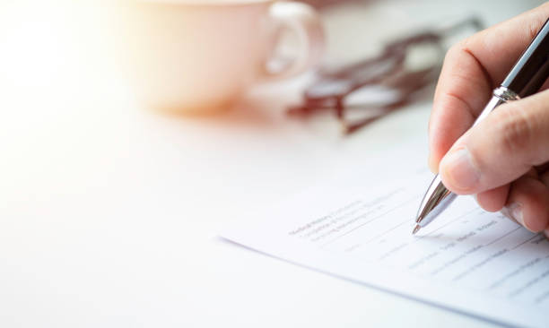 istock Close-up of Hand using writing pen with questionnaire or paperwork survey question filling 1343271880