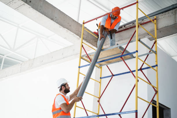 istock Two men builder in uniform drag the pipe on scaffolding at construction site 1343273426