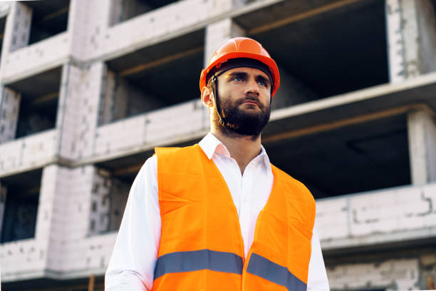 istock Builder wearing hardhat and safety vest standing on a commercial construction site 1343274307