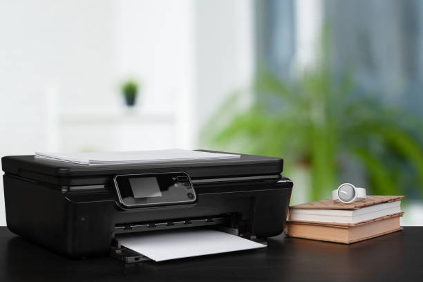 istock Stack of books and home printer against blurred background 1343277661