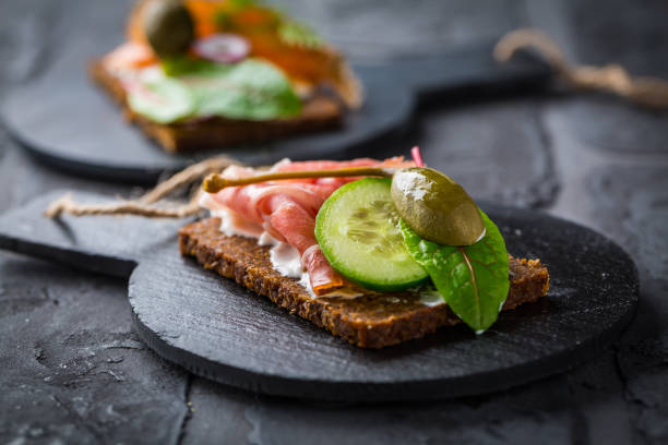 istock Open sandwich with prosciutto on black bread (pumpernickel) on cutting board 1343283587