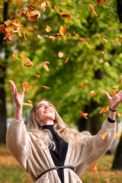 istock Happy girl with pretty face catches falling leaves from a tree 1343284590