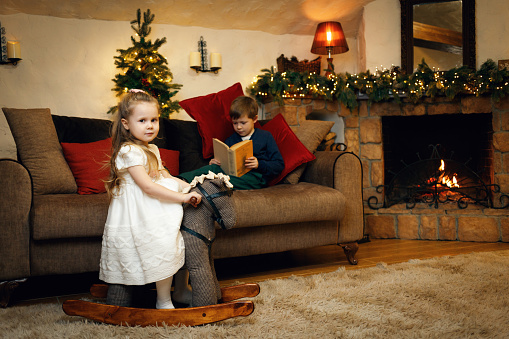 Brother and sister in anticipation of the new year, spend time in the room decorated with garlands