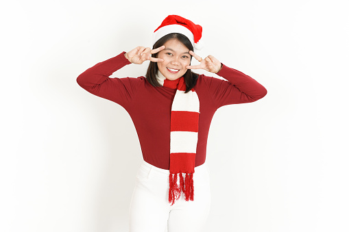 Showing Peace or Victory Sign of Beautiful Asian Woman Wearing Red Turtleneck and Santa Hat Isolated On White Background