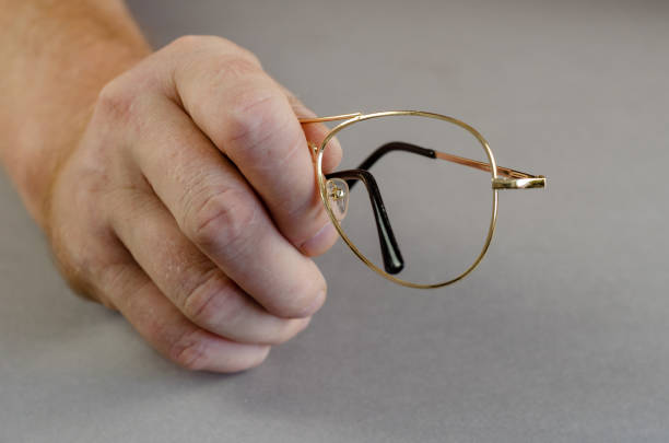 istock One hand holds an empty metal eyeglass frame against a gray back 1343286514