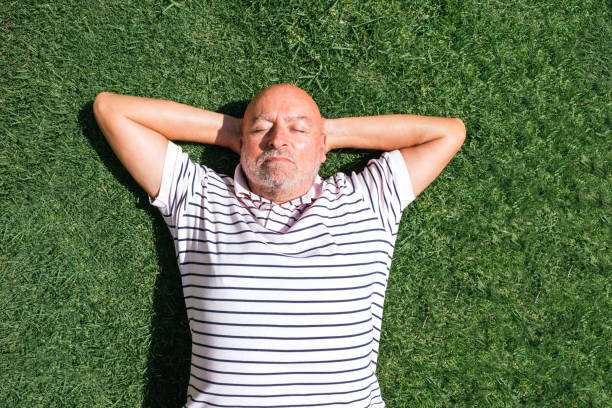 istock Retired man resting head resting on arms on the grass with his hands on his head with grass background 1343290641