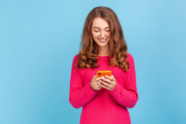 istock Woman using cellphone and smiling, reading good news message, enjoying mobile application. 1343292591