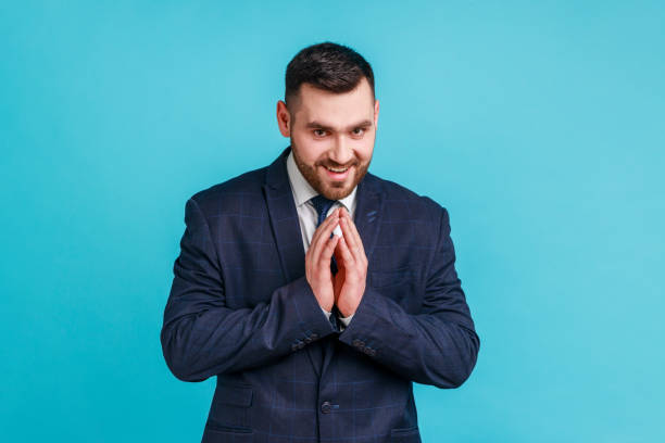 retrato de un apuesto hombre moreno con barba con traje oscuro de estilo oficial, pensando en trucos y trampas tortuosas, mirando a la cámara. - venganza fotografías e imágenes de stock