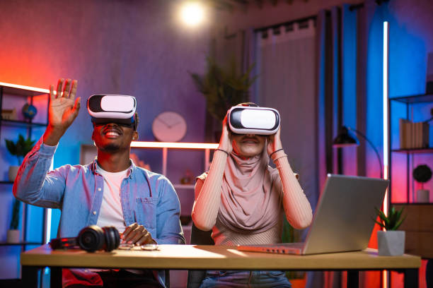 istock Diverse couple sitting at desk in VR glasses playing games 1343298663