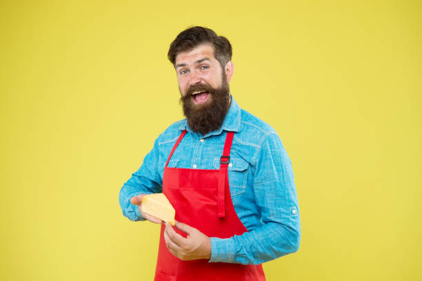 Lactose. Gourmet product. Dairy product derived from milk. Cheese making techniques. Online shopping. Diet and nutrition. Cheesemaking concept. Cheese maker. Bearded man in apron hold piece cheese.