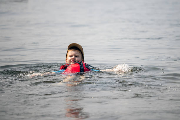 giovane ragazzo che nuota nel lago durante l'estate - life jacket little boys lake jumping foto e immagini stock