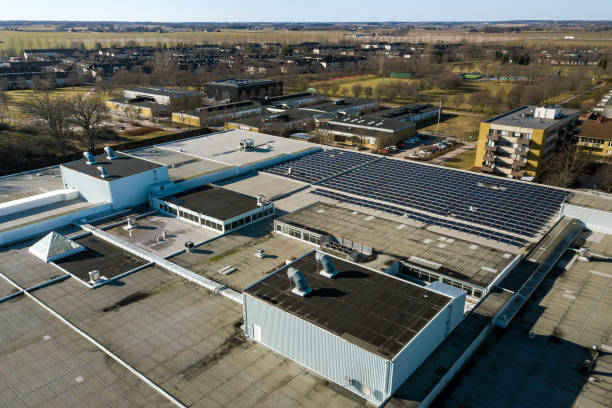 vue aérienne de panneaux solaires photovoltaïques bleus montés sur le toit d’un bâtiment industriel pour produire de l’électricité écologique verte. concept de production d’énergie durable. - production dénergie photos et images de collection
