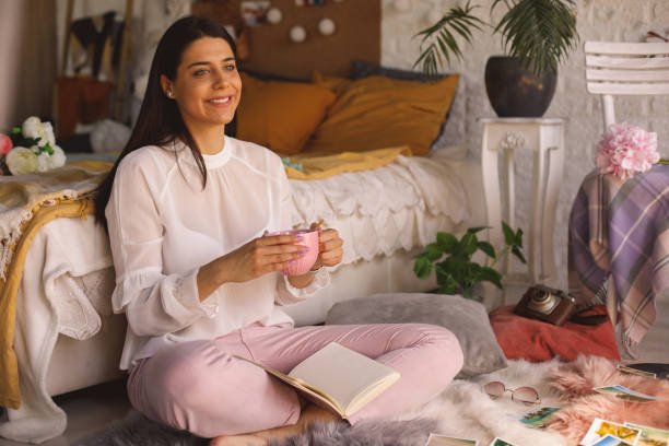 istock Young woman enjoying a cup of tea while reading a book 1343303949