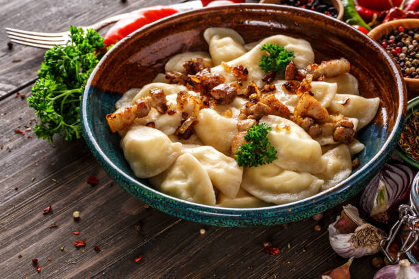 Pierogi or pyrohy, varenyky, vareniki, dumplings served with caramelized salted onion in bowl on wooden table - traditional Ukrainian food Pierogi or pyrohy, varenyky, vareniki, dumplings served with caramelized salted onion in bowl on wooden table - traditional Ukrainian food pierogi stock pictures, royalty-free photos & images