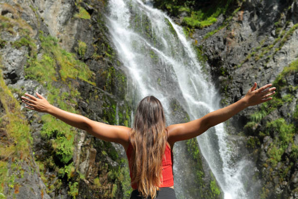 istock Single woman outstretching arms in a waterfall 1343306403