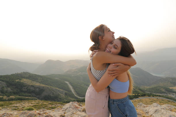 Two happy friends hugging in nature stock photo