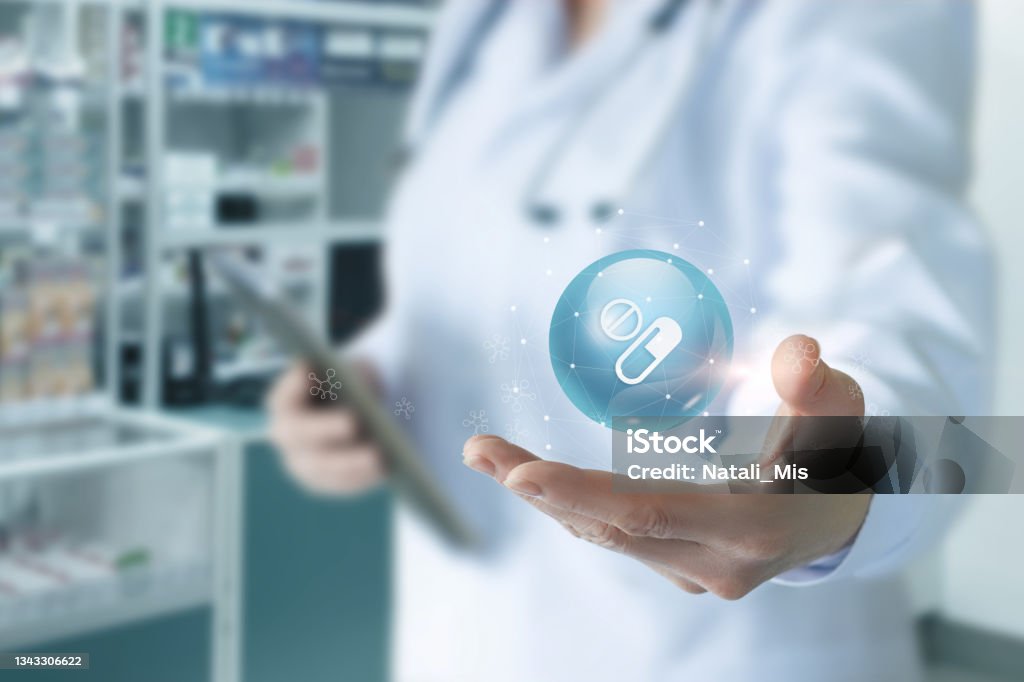 Doctor shows medicine and pills icon . Doctor shows medicine and pills icon on blurred background of pharmacy. Pharmacy Stock Photo
