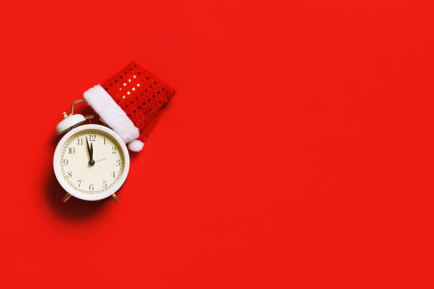 istock Alarm clock with a Christmas cap on a red background with copy space. New Years celebration concept. 1343308137