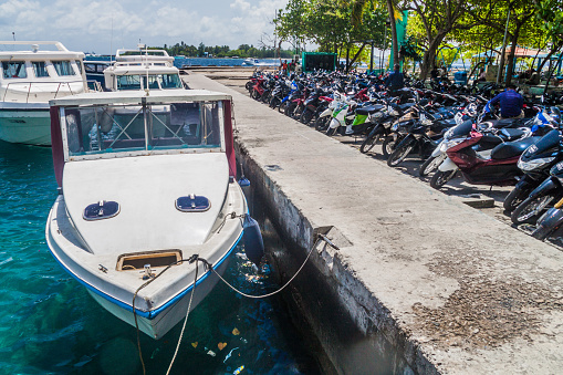 Male, Maldives - July 11, 2016: Boats anchored next to motorcycle parking lot in Male.