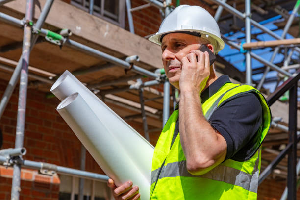 istock Male builder foreman, worker or architect on construction site holding building plans and talking on his cell phone 1343315591