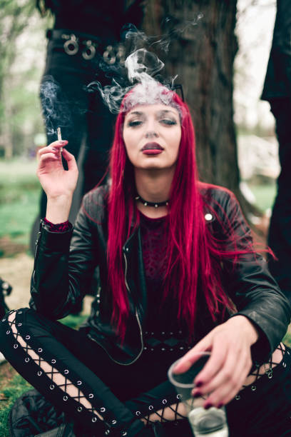 istock Beautiful Female Goth Smoking Cigarette And Drinking Alcohol In Park 1343315725