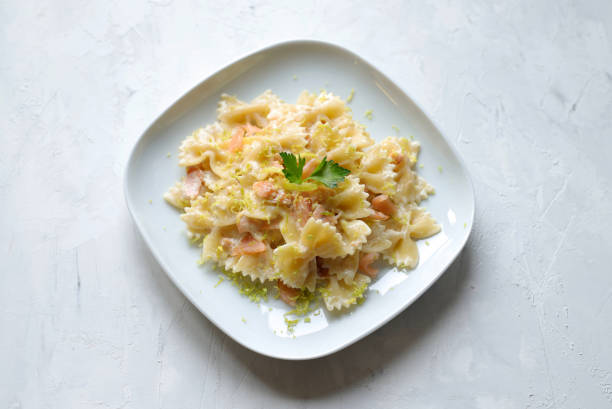 Farfalle pasta with smoked salmon, a cream sauce and lemon on white plate. Italian food.