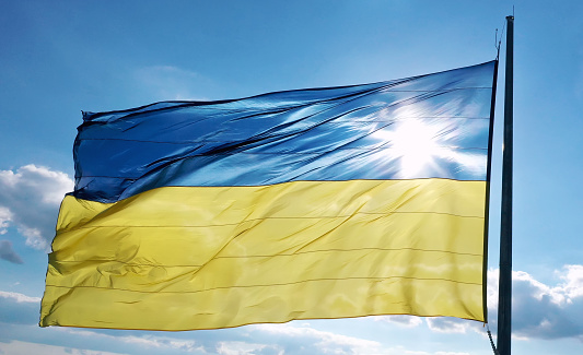The flag of Ukraine develops on a flagpole against a background of clear sky