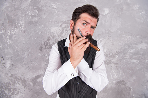 A handsome man in a suit is smoking a cigar in the dark